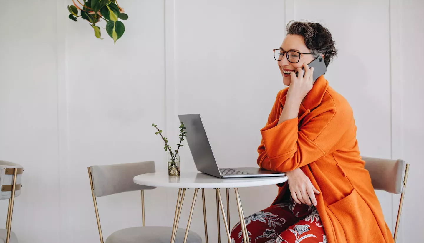 Frau schaut auf Laptop und benutzt das Telefon