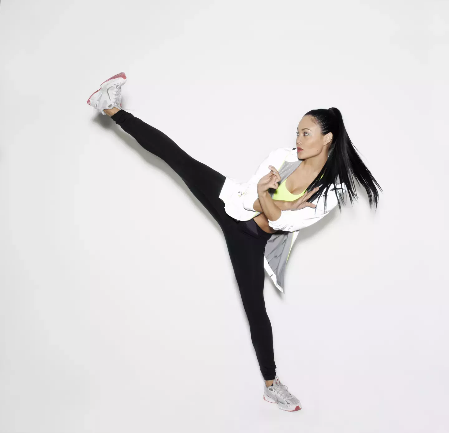 Entschlossene athletische Frau hoch kicken