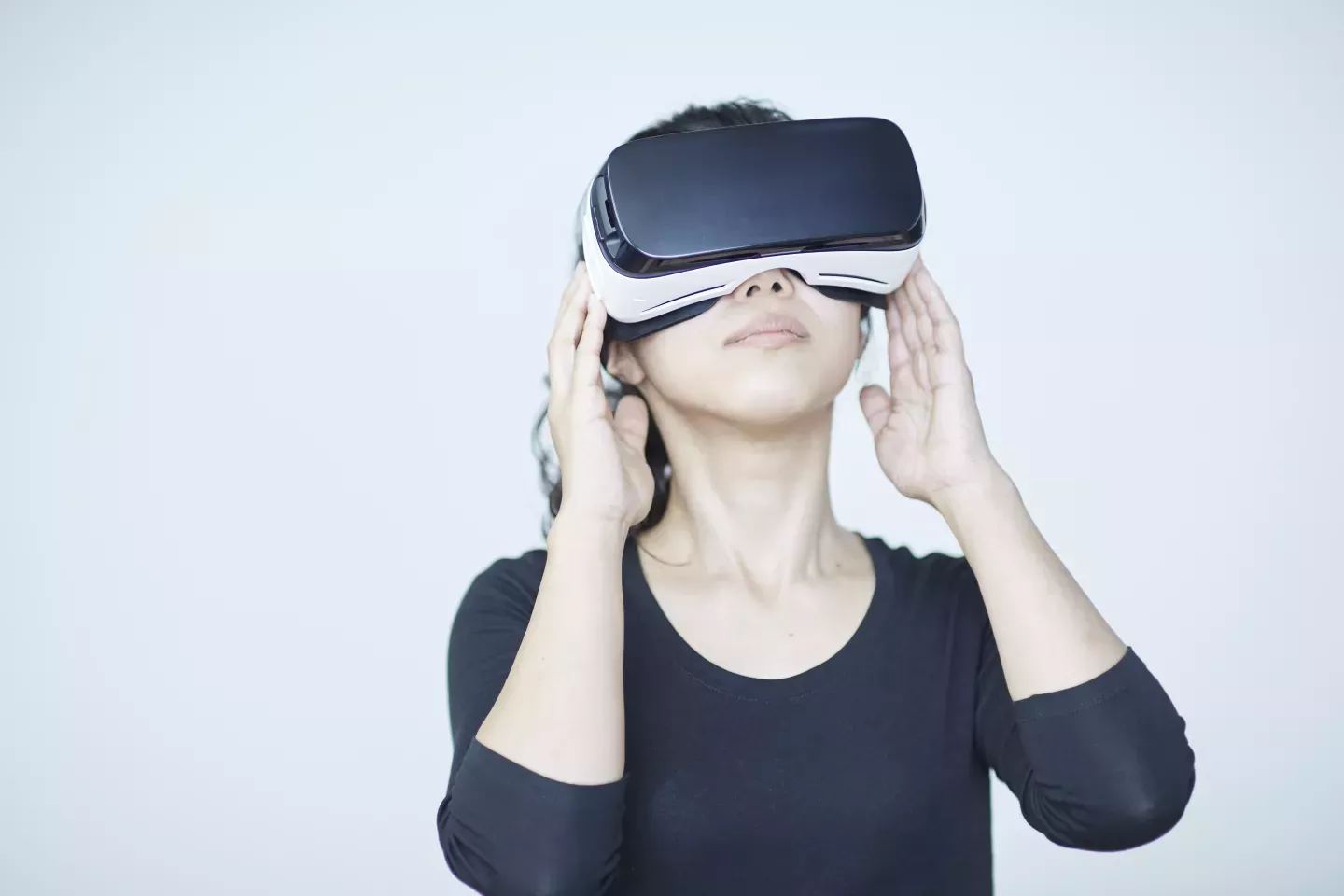 Frau hält Virtual-Reality-Headset an die Augen und schaut nach oben woman holding virtual reality headset to eyes and looking up