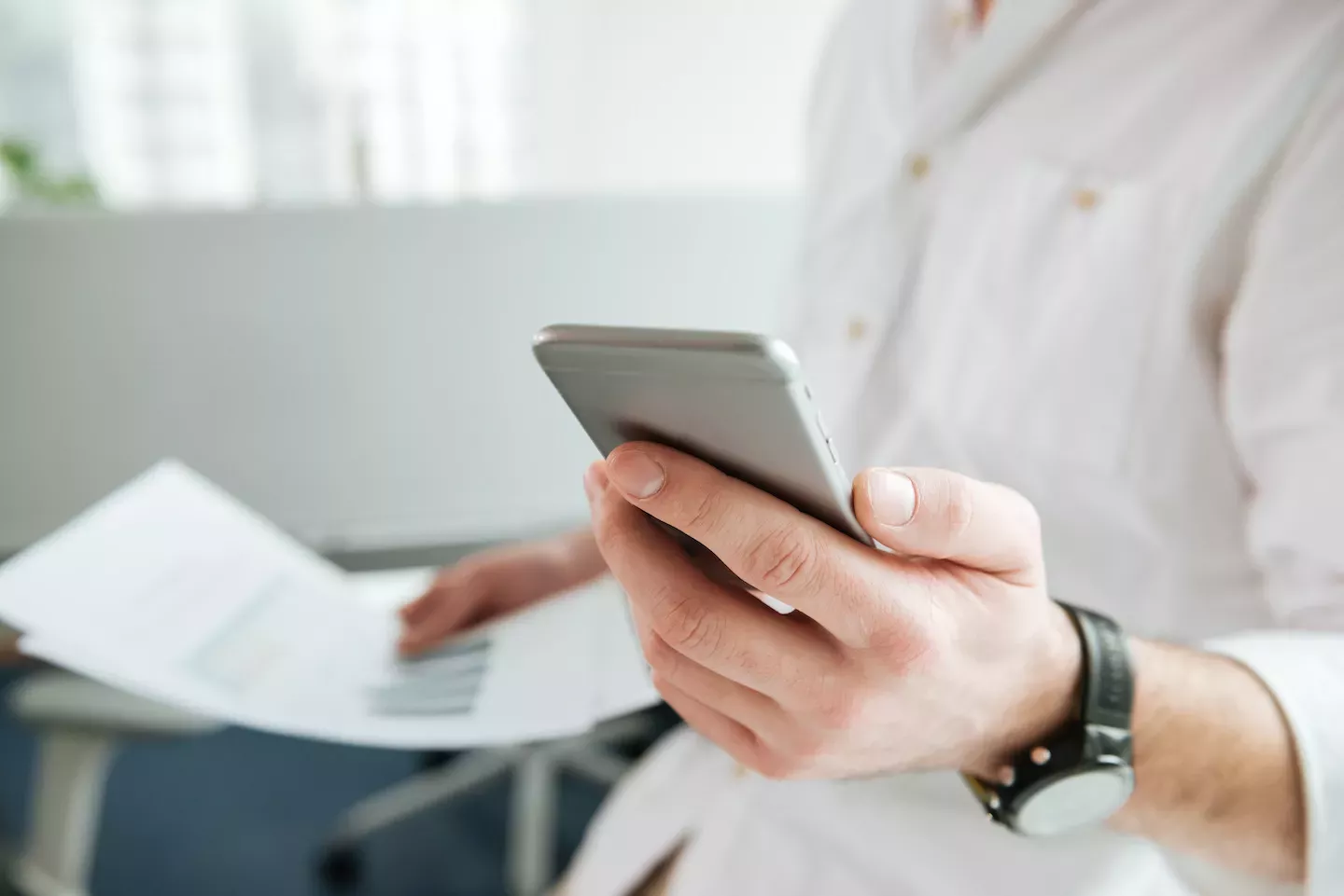 Person, die ein Telefon benutzt und Papiere in der Hand hält