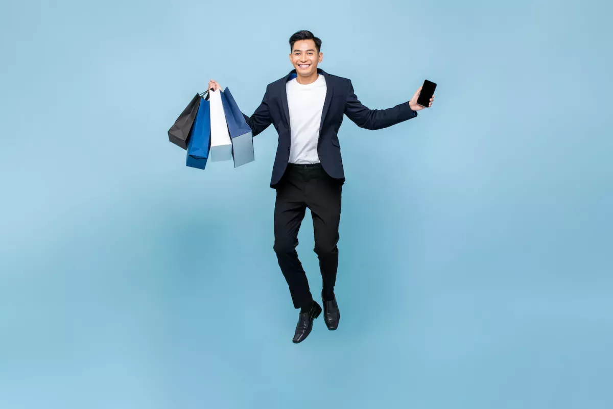 Hombre saltando con bolsas de compras y un teléfono