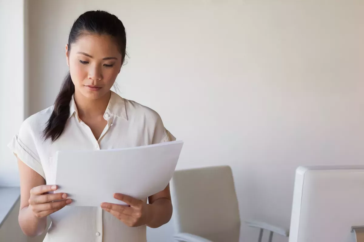 Mujer en una oficina leyendo papeles Mujer en una oficina leyendo papeles