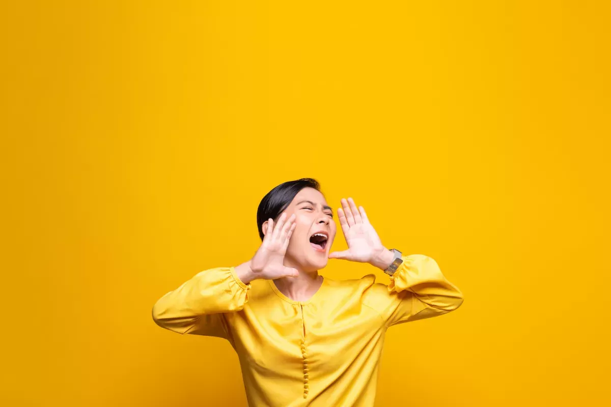 Mujer gritando con una camisa amarilla