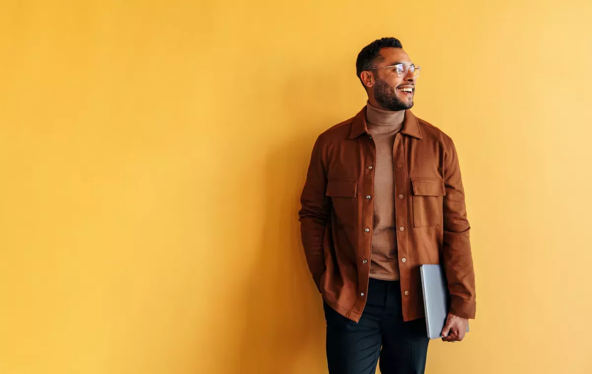 Hombre sonriente sosteniendo una computadora portátil