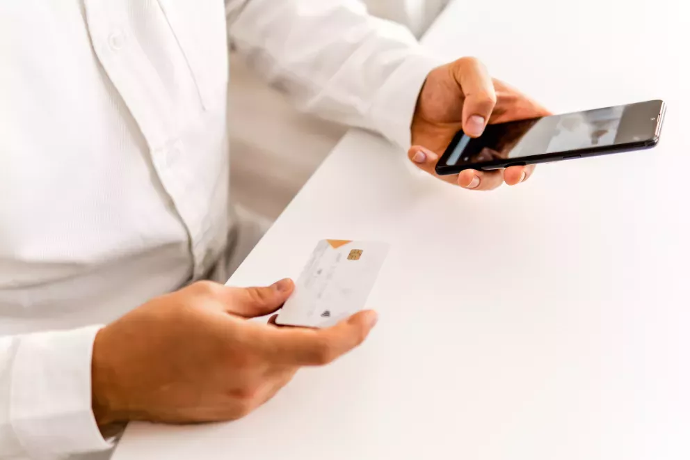 Primer plano de una persona comprando en el teléfono celular con tarjeta de crédito