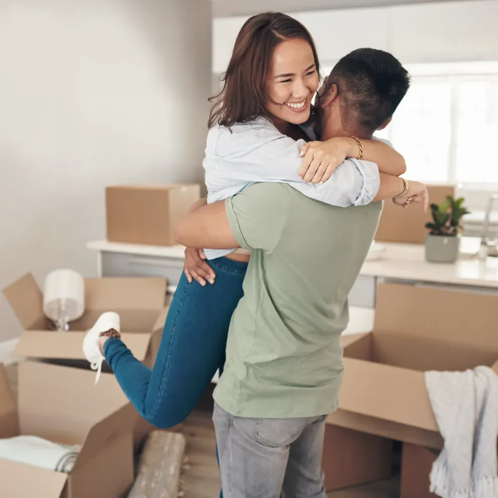 Pareja emocionada abrazándose en su nuevo hogar