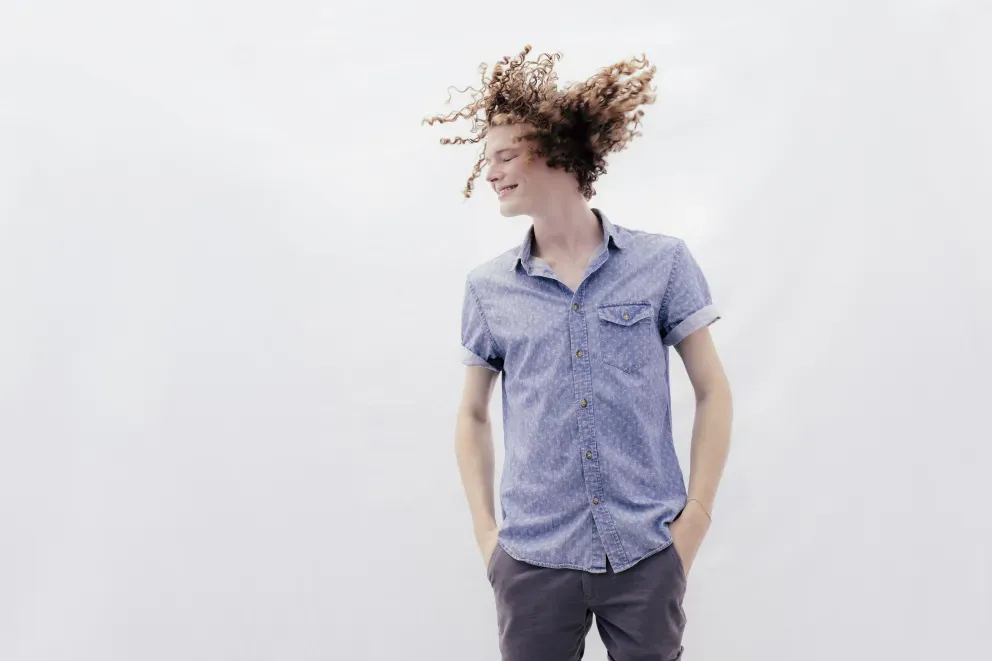 hombre sonriente sacudiendo el cabello libremente por el aire