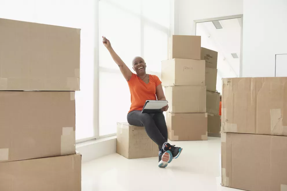 Persona sentada en cajas en movimiento exclamando con emoción