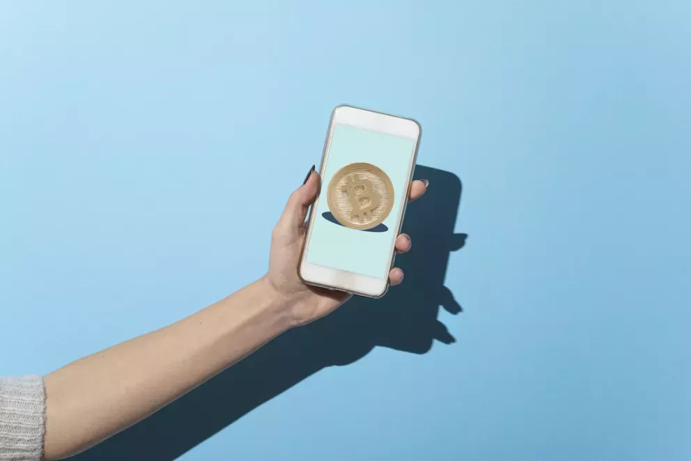 Persona sosteniendo un teléfono con una imagen de bitcoin Persona sosteniendo un teléfono con una imagen de bitcoin