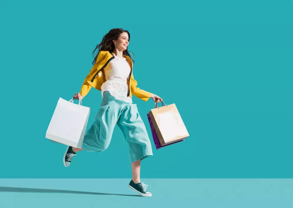 Mujer saltando con bolsas de la compra