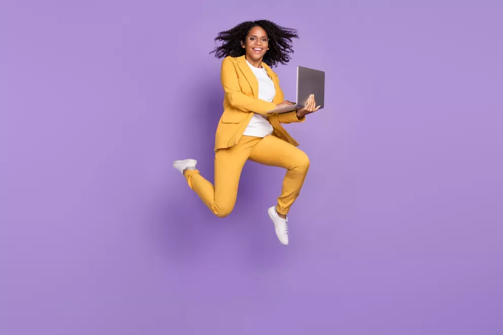 Mujer saltando con laptop