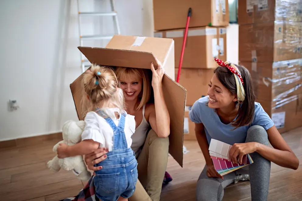 pareja jugando con un niño pequeño y una caja de mudanza