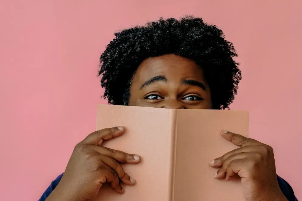 man hiding behind book