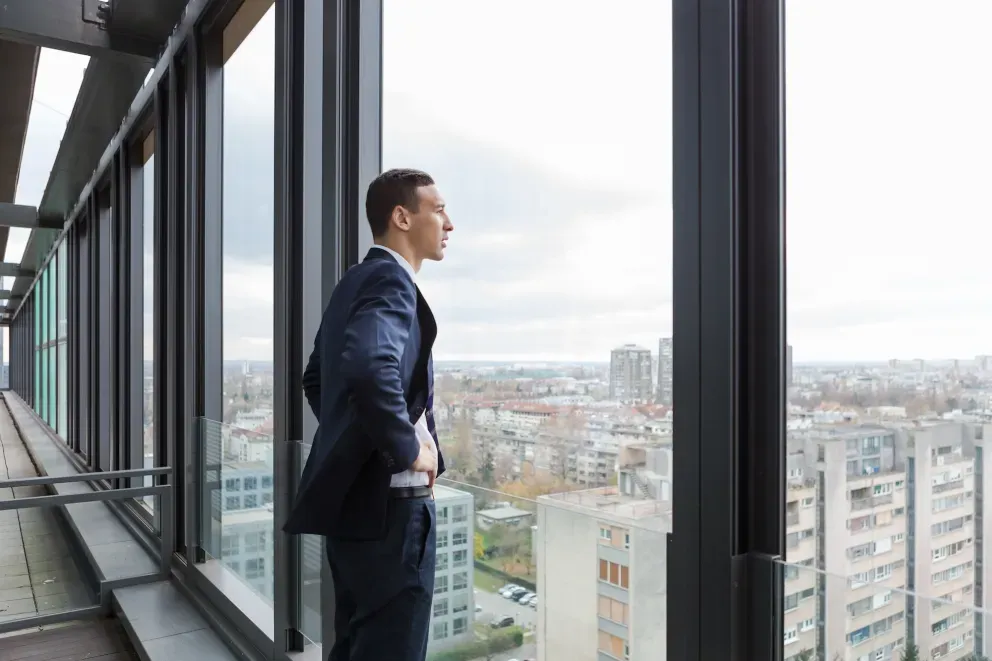 Businessman looking into distance of city in high rise Businessman looking into distance of city in high rise