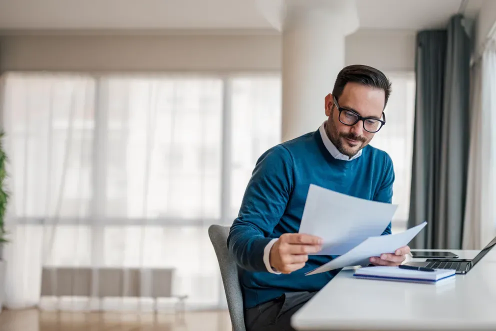 Hombre sentado en un escritorio mirando documentos