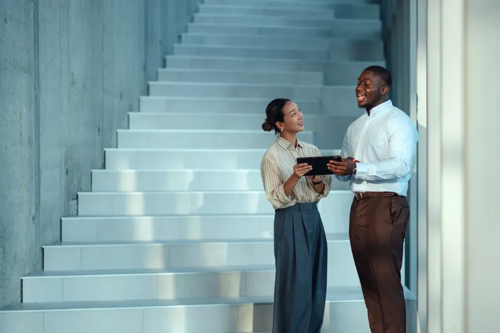 Dos empresarios colaborando al pie de una escalera