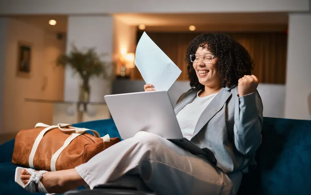 Mujer relajándose en el sofá con una computadora portátil, vistiendo ropa informal en un acogedor entorno de sala de estar.