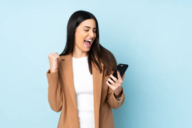 woman looking at cell phone exclaiming with joy woman looking at cell phone exclaiming with joy