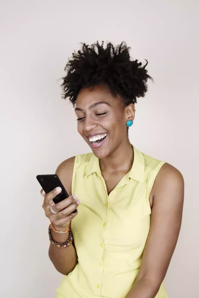 mujer sonriente mirando un teléfono celular