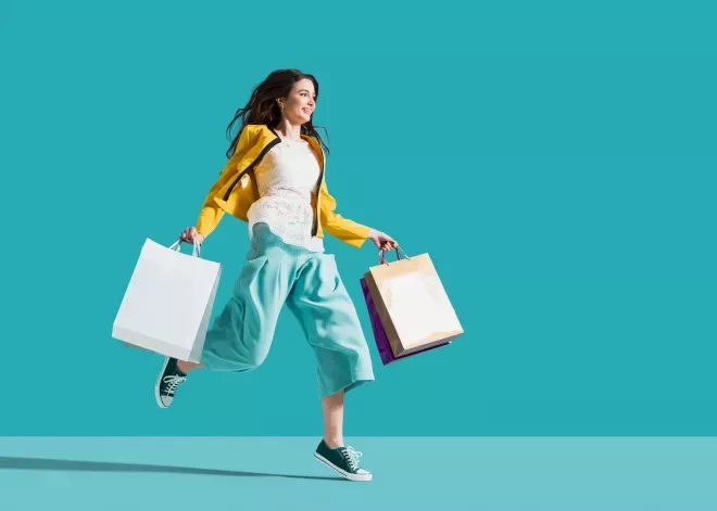 Mujer saltando sosteniendo bolsas de compras