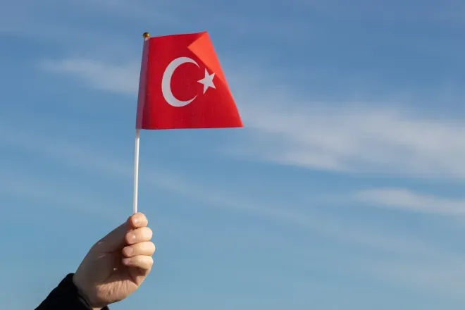 Hand holding Turkish flag in sky