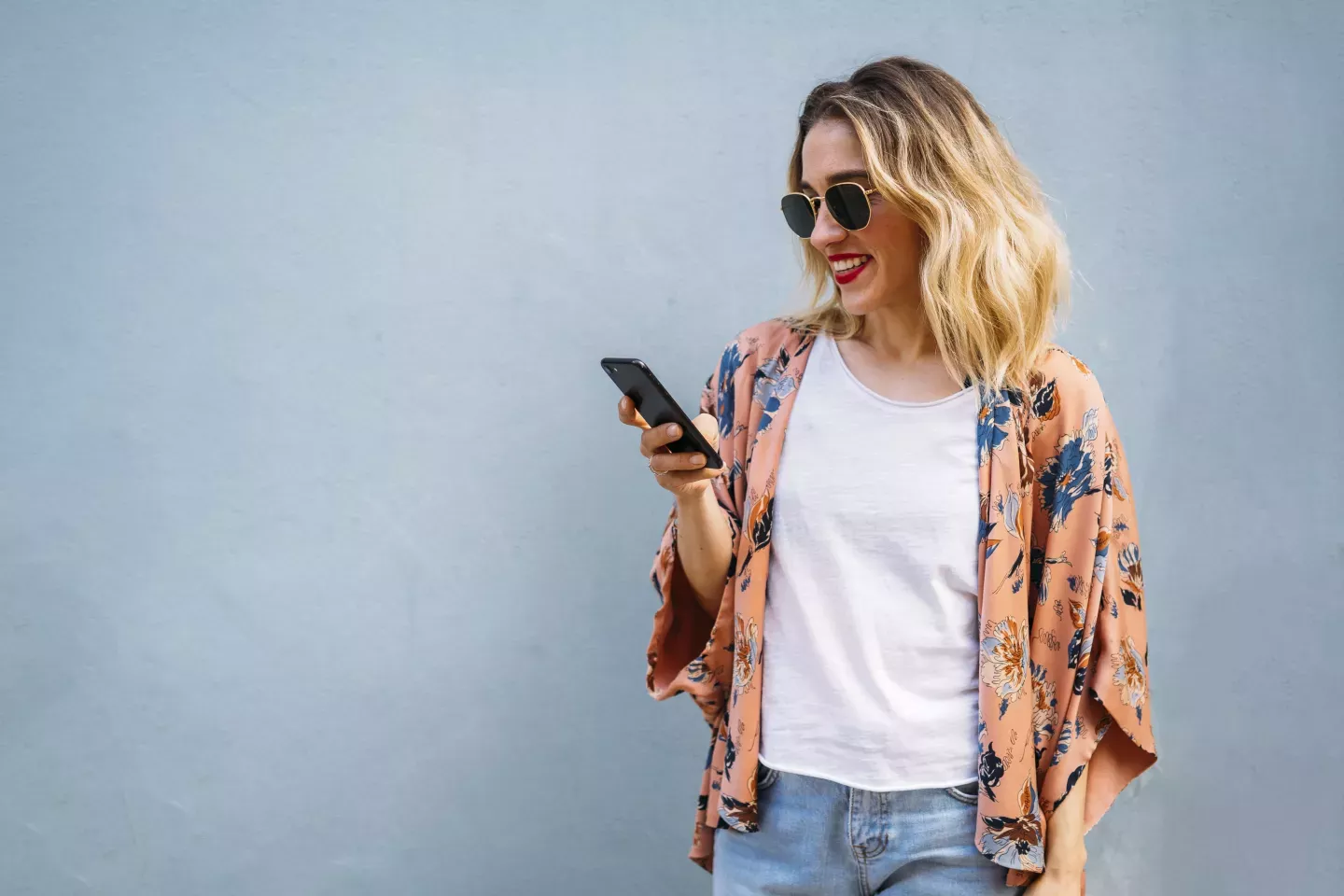 mujer sonriente mirando un teléfono celular
