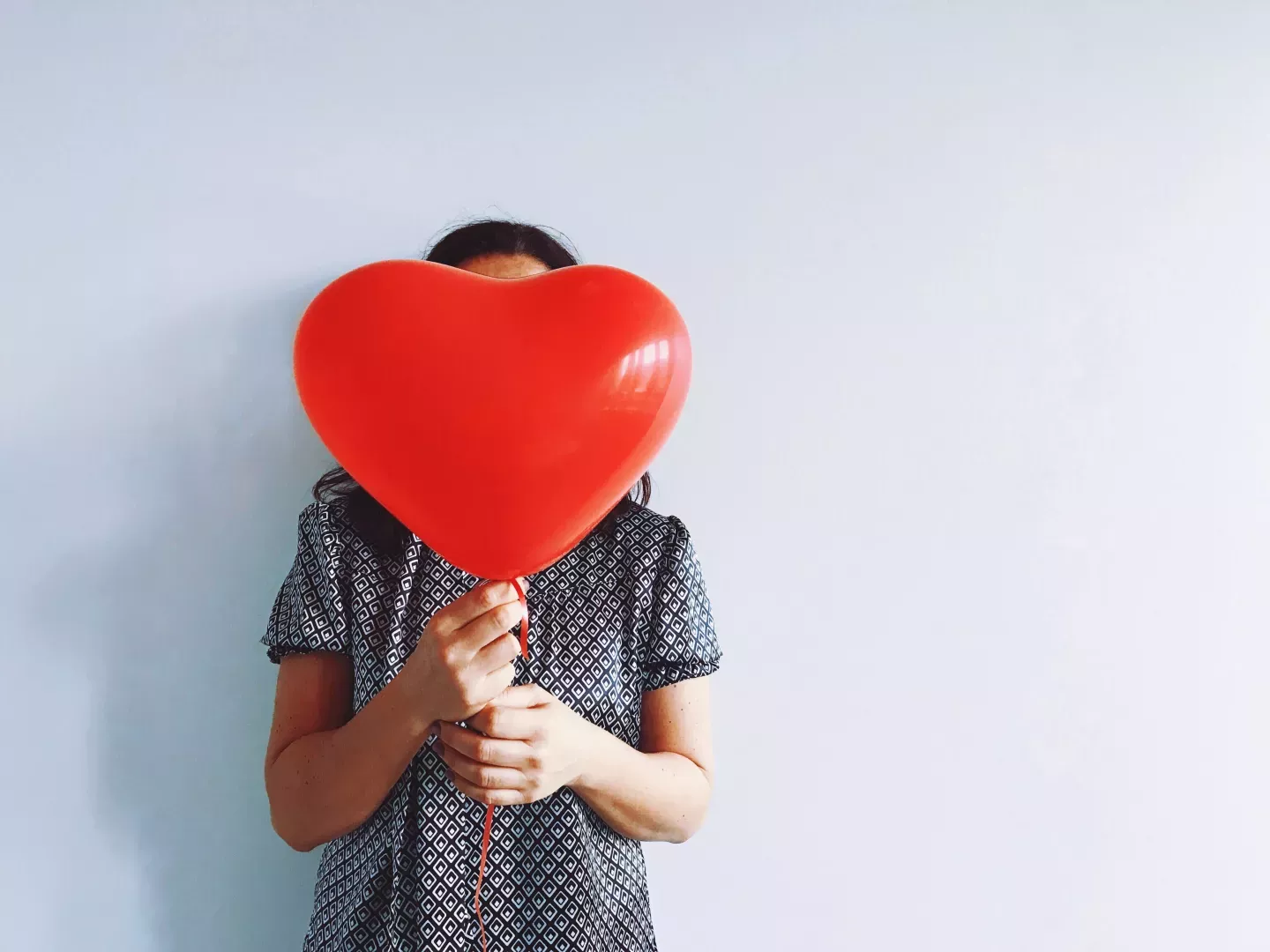 Mujer sosteniendo un globo rojo en forma de corazón