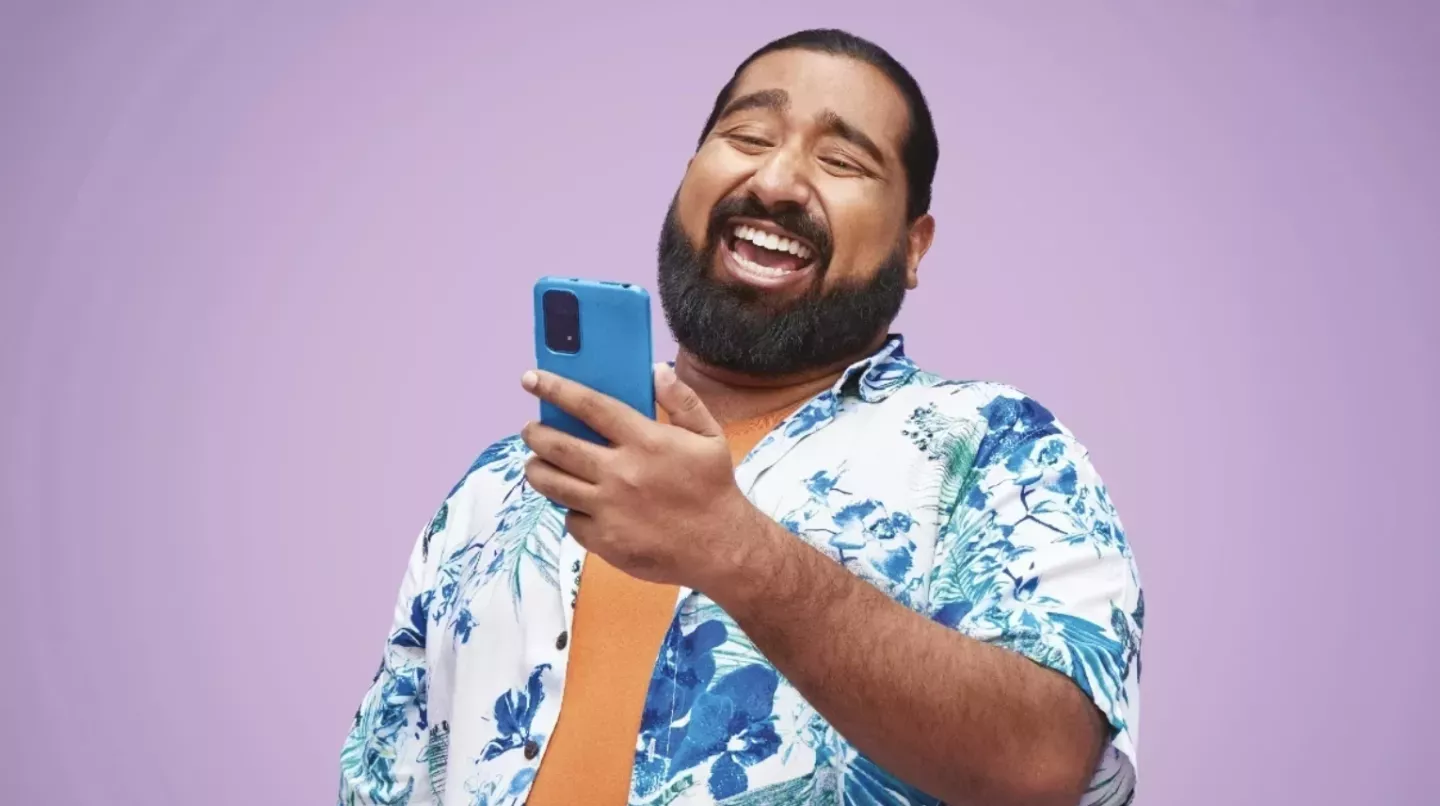 Hombre mirando un teléfono móvil y riendo