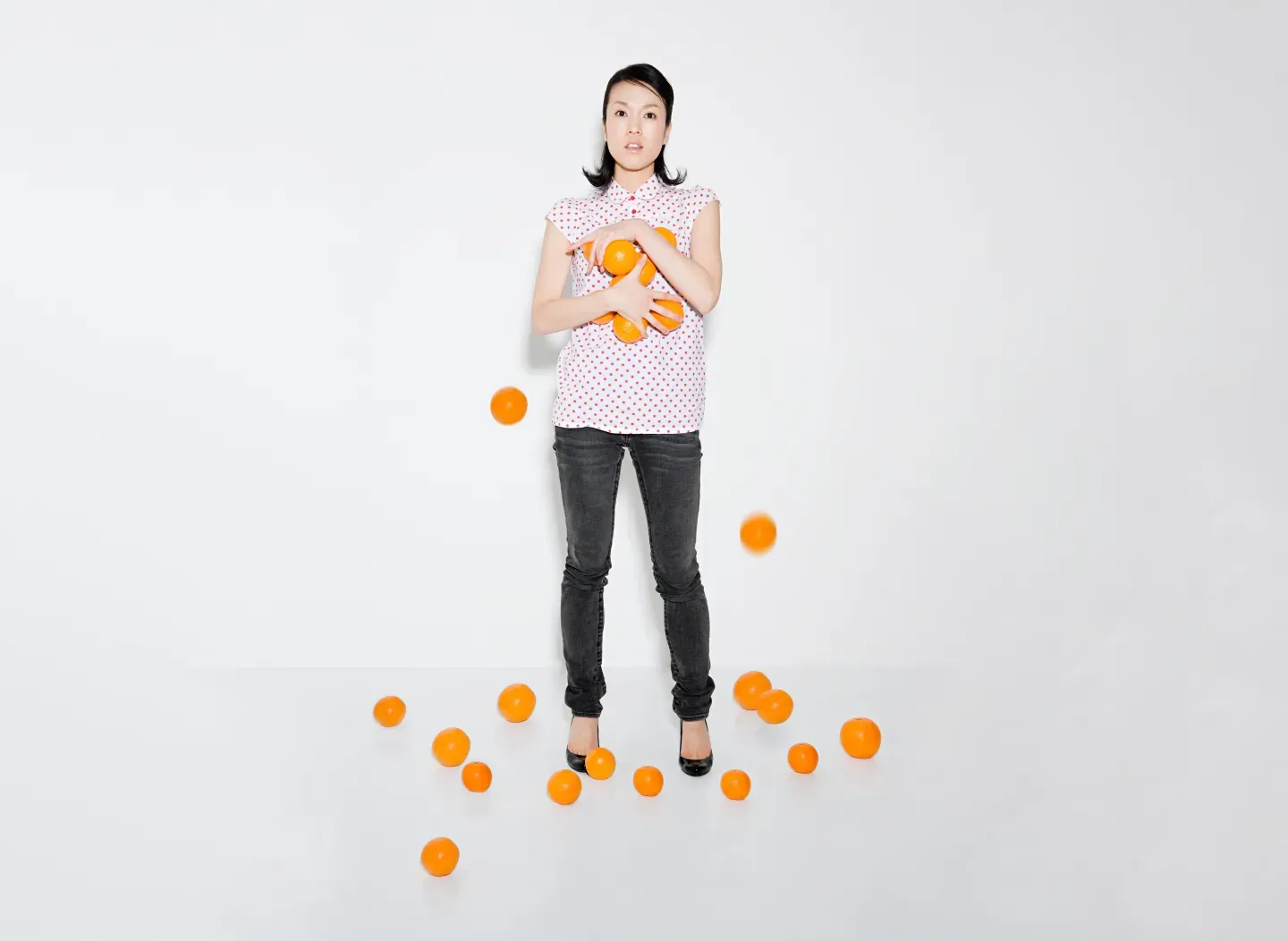 Mujer luchando por sostener naranjas