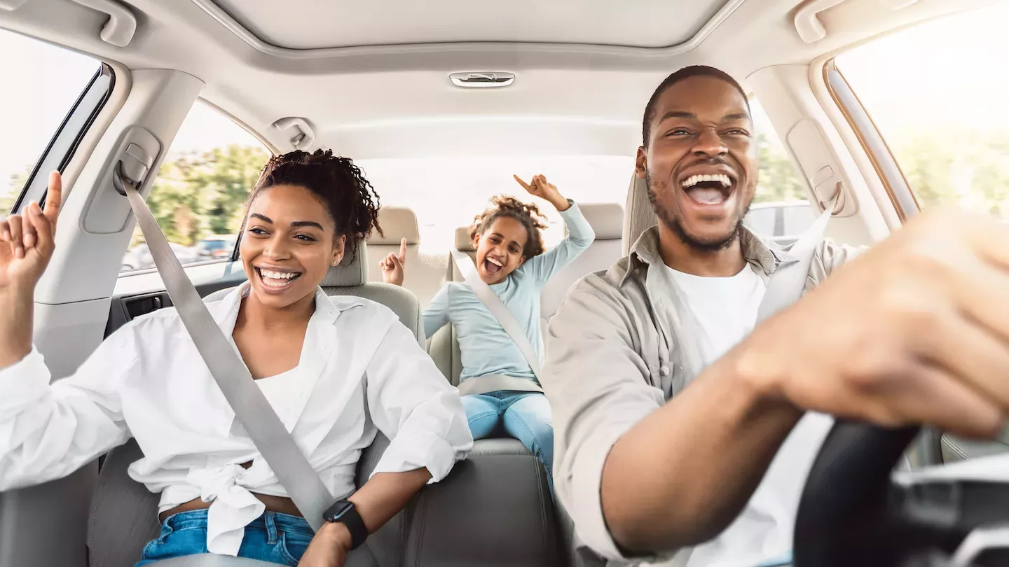 Familia feliz conduciendo un coche nuevo