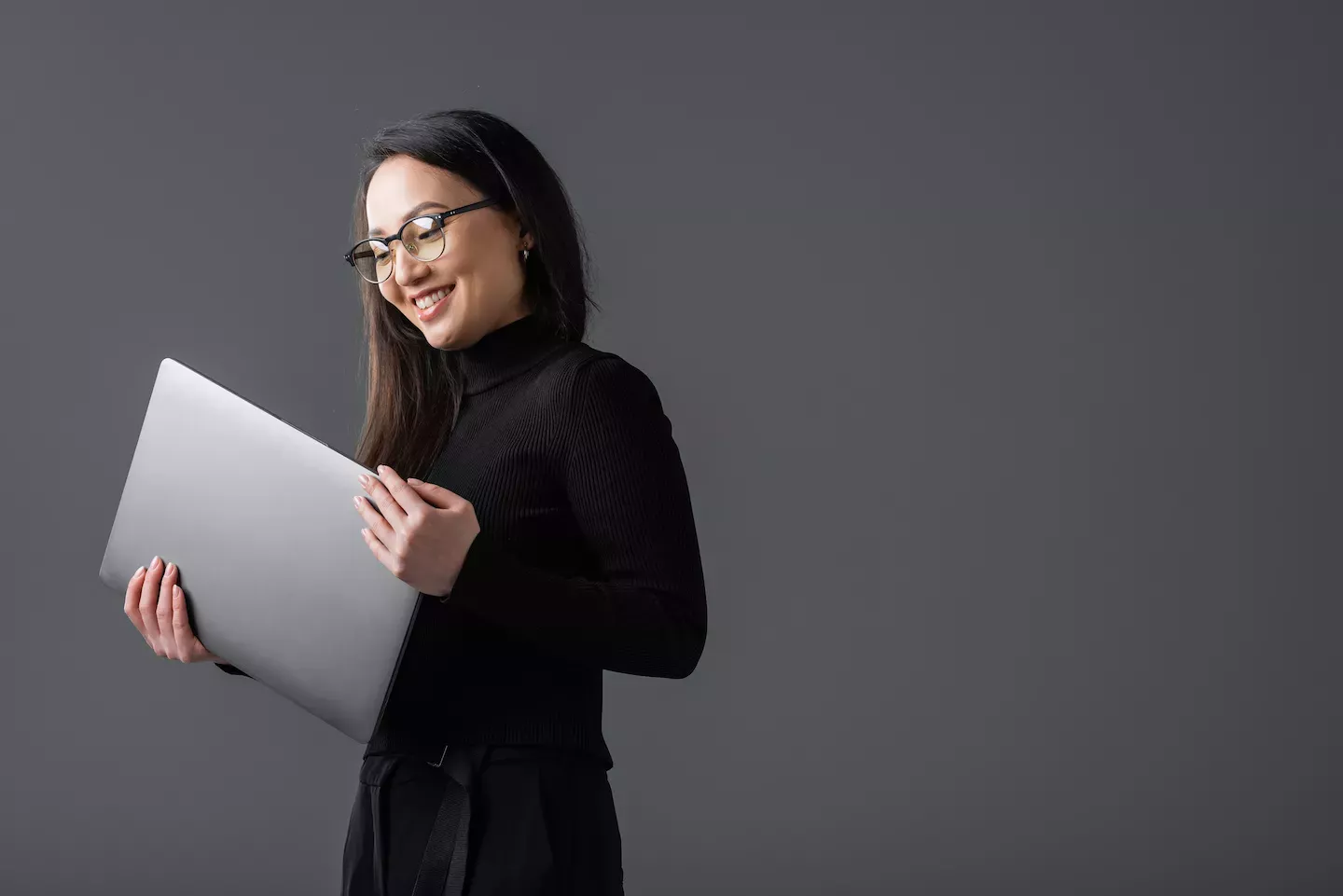 Mujer sonriendo y sosteniendo una computadora portátil