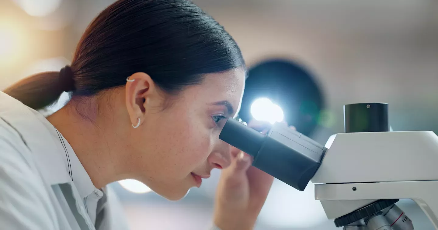 Persona mirando a través del microscopio