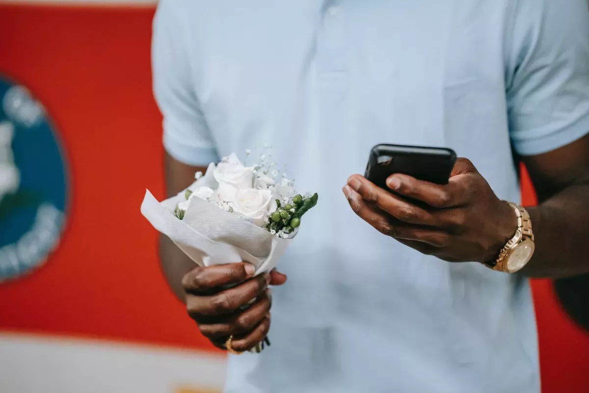 -8554863.jpg_FICO Customer Communications Services close up of person holding small bouquet of white flowers and using cell phone