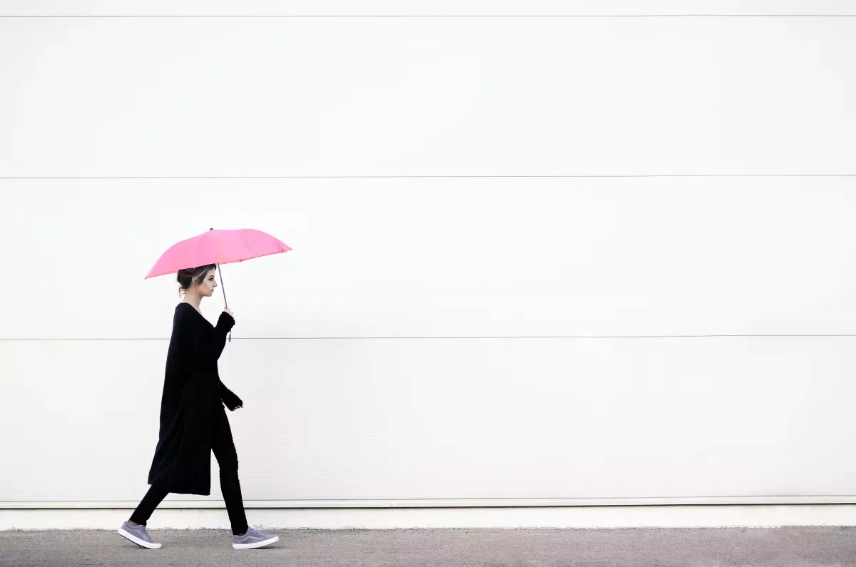 AdobeStock_136754314.jpeg woman walking with pink unbrella