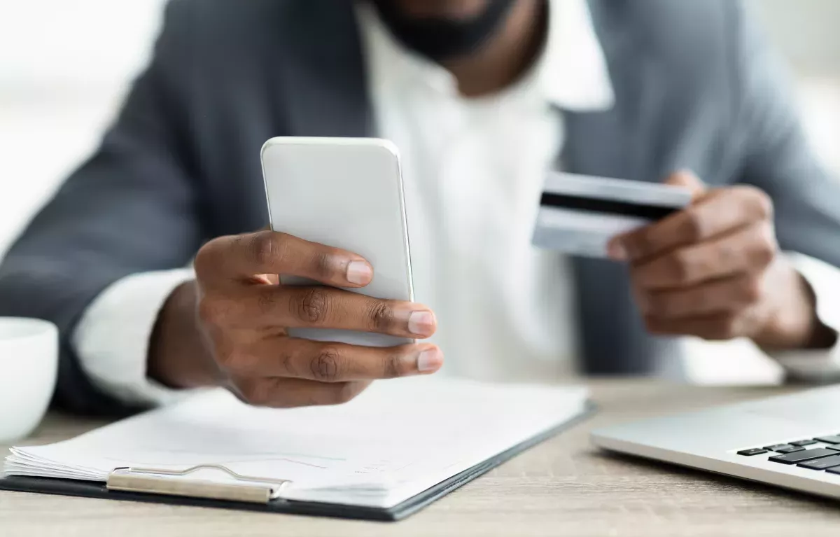 AdobeStock_282680830.jpeg close up of person using credit card to pay on cell phone