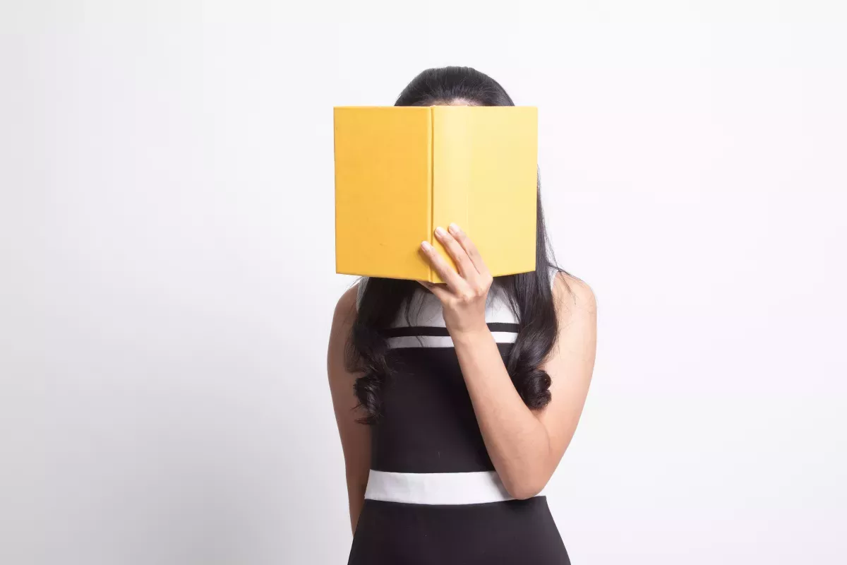 AdobeStock_310130102.jpeg person covering face with big yellow book