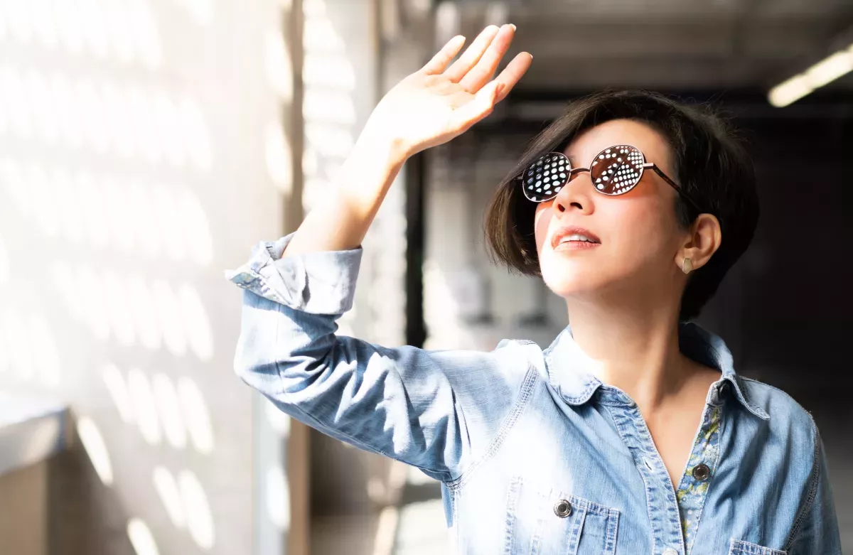 AdobeStock_316695592_Protect & Comply woman in sunglasses holding hand up to block the sun