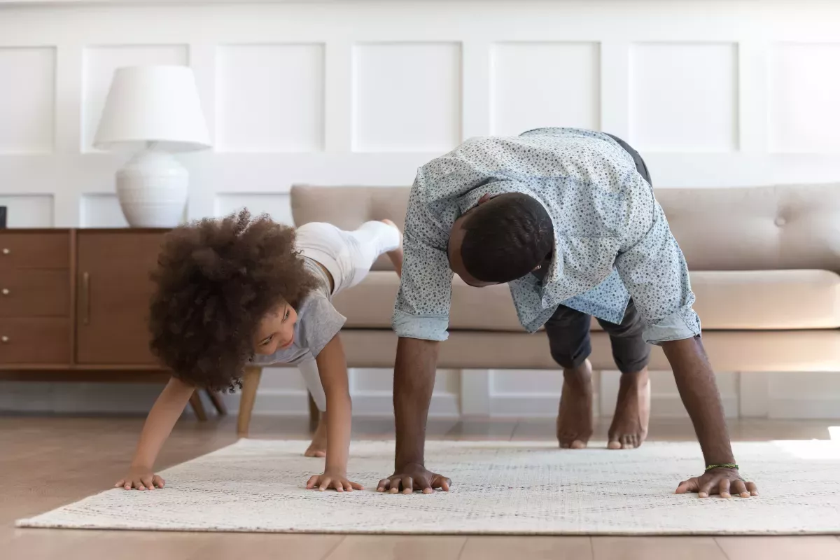 AdobeStock_317577446_Nurture & Manage father and young daughter doing push-up exercise indoors
