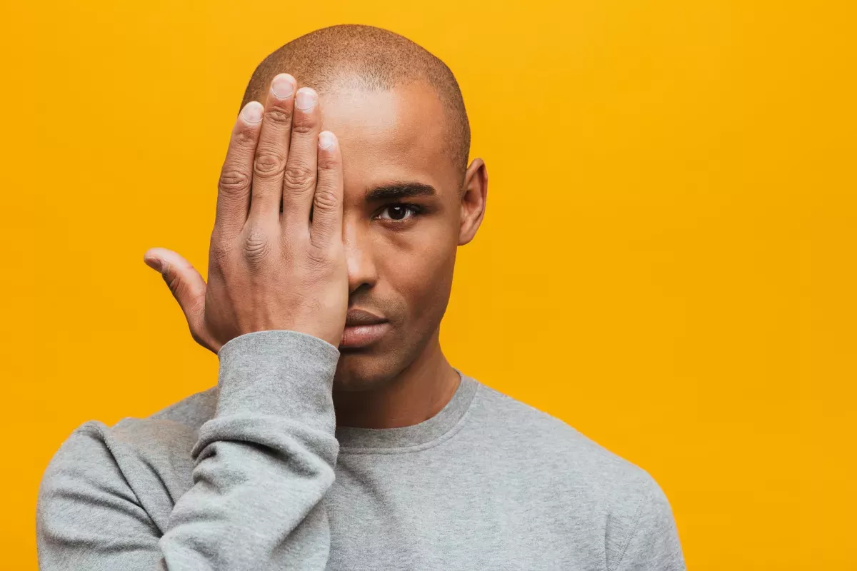 AdobeStock_319420336.jpeg man covering half of face with hand