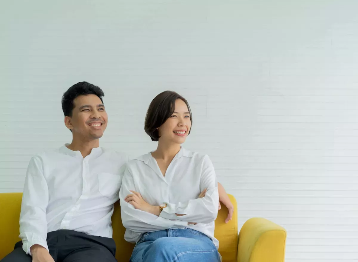 AdobeStock_379677397.jpeg Happy couple sitting on a yellow couch