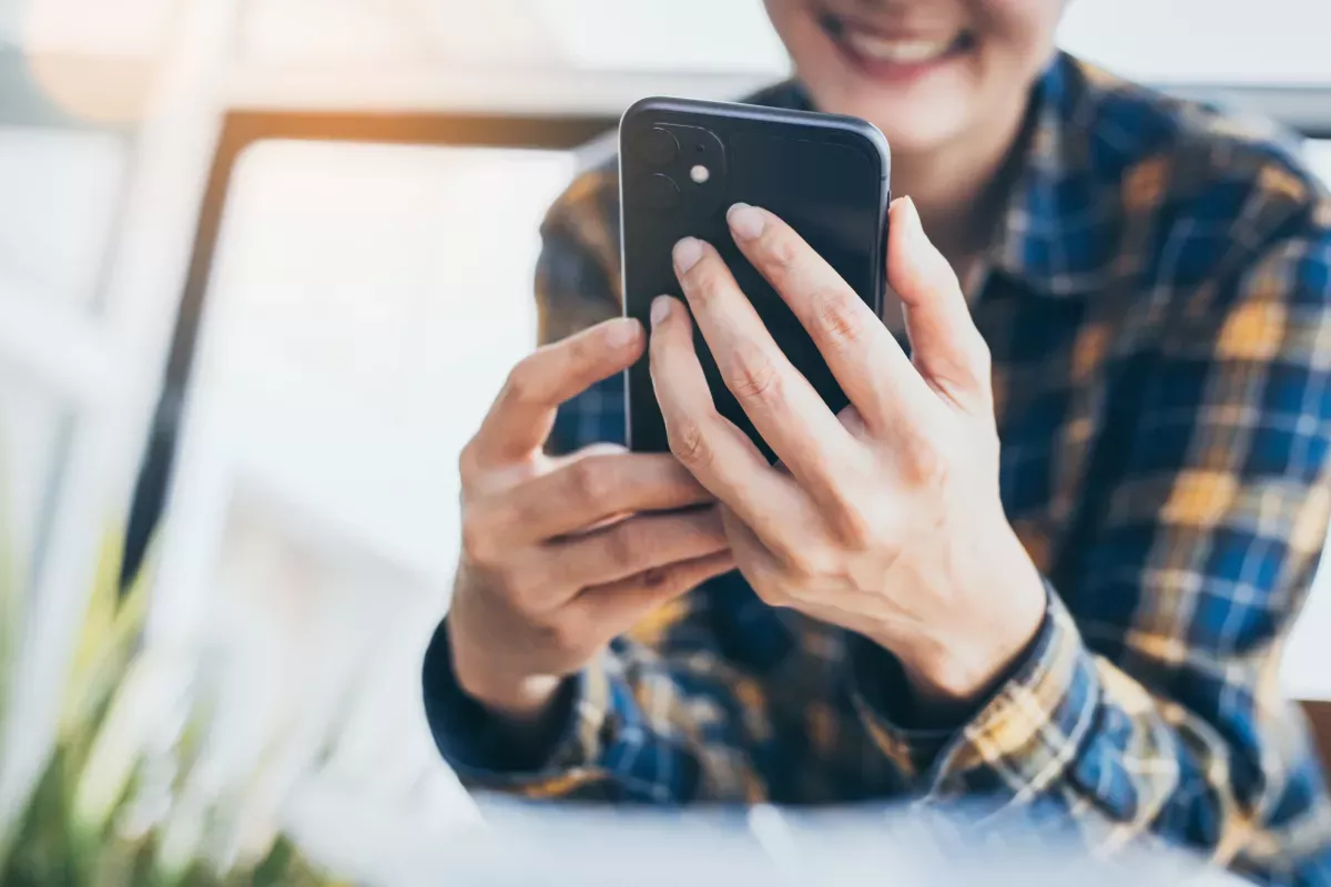 AdobeStock_404693542_Nurture & Manage smiling woman using cell phone in a sunny room