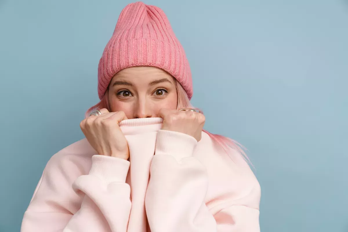 AdobeStock_433424218_Protect & Comply woman with shocked expression hiding mouth by pulling up sweatshirt