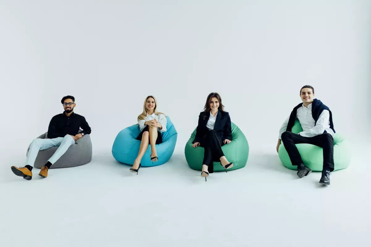 young multicultural colleagues discussing project sitting on large beanbags