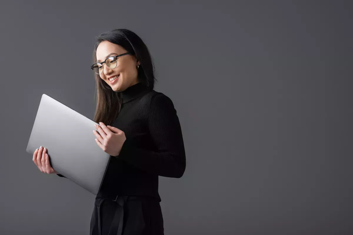 AdobeStock_566247441.jpeg Woman smiling and holding a laptop