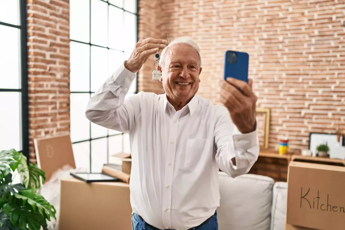 C_20.jpeg excited man holding new house keys up to phone to take selfie