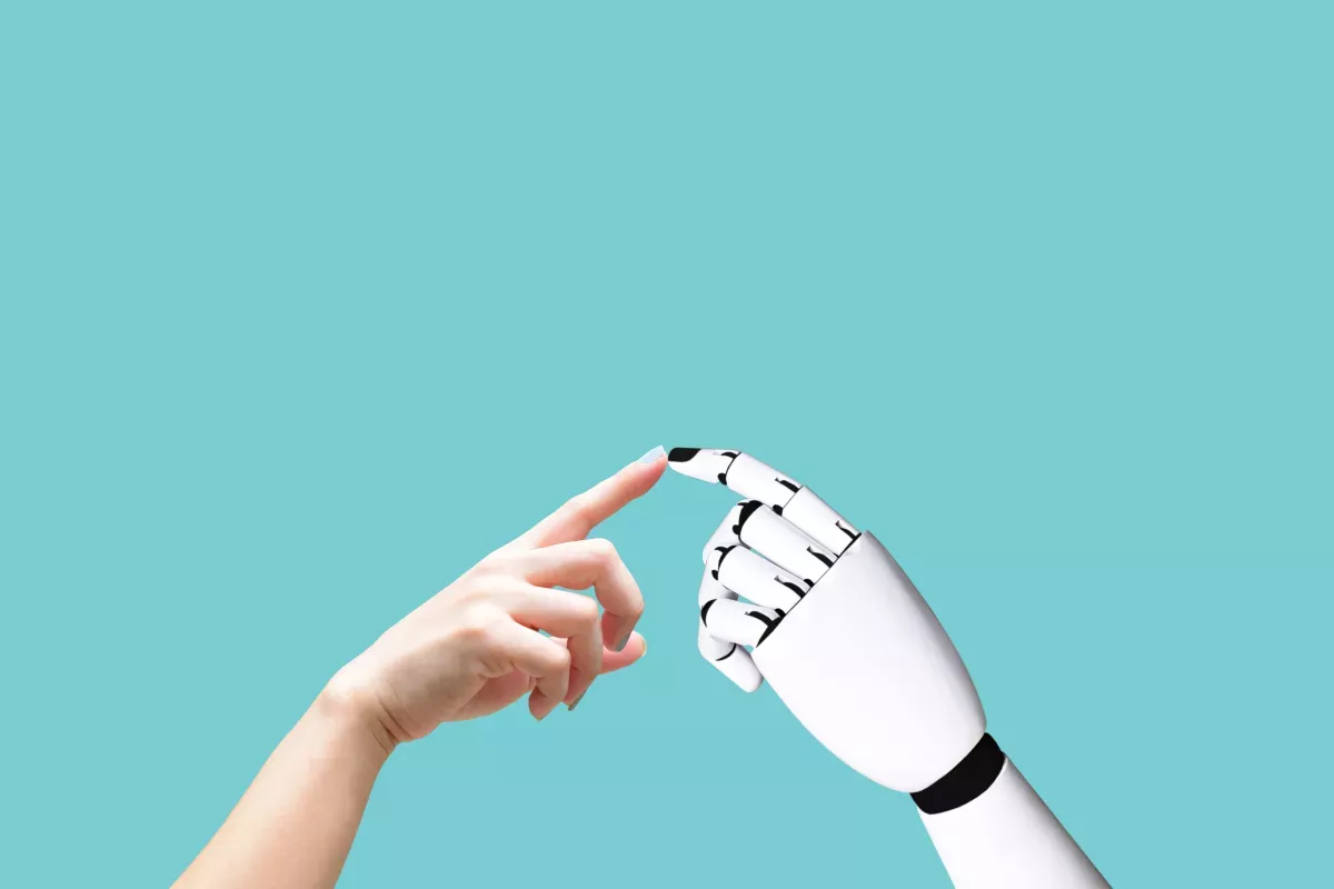 Artificial intelligence robot hand reaching out to human hand in caring way