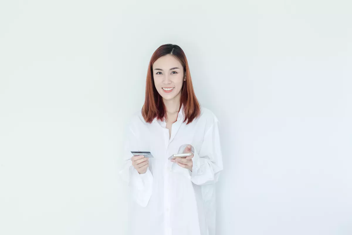 GettyImages-1156744142.jpg smiling woman holding cell phone and credit card