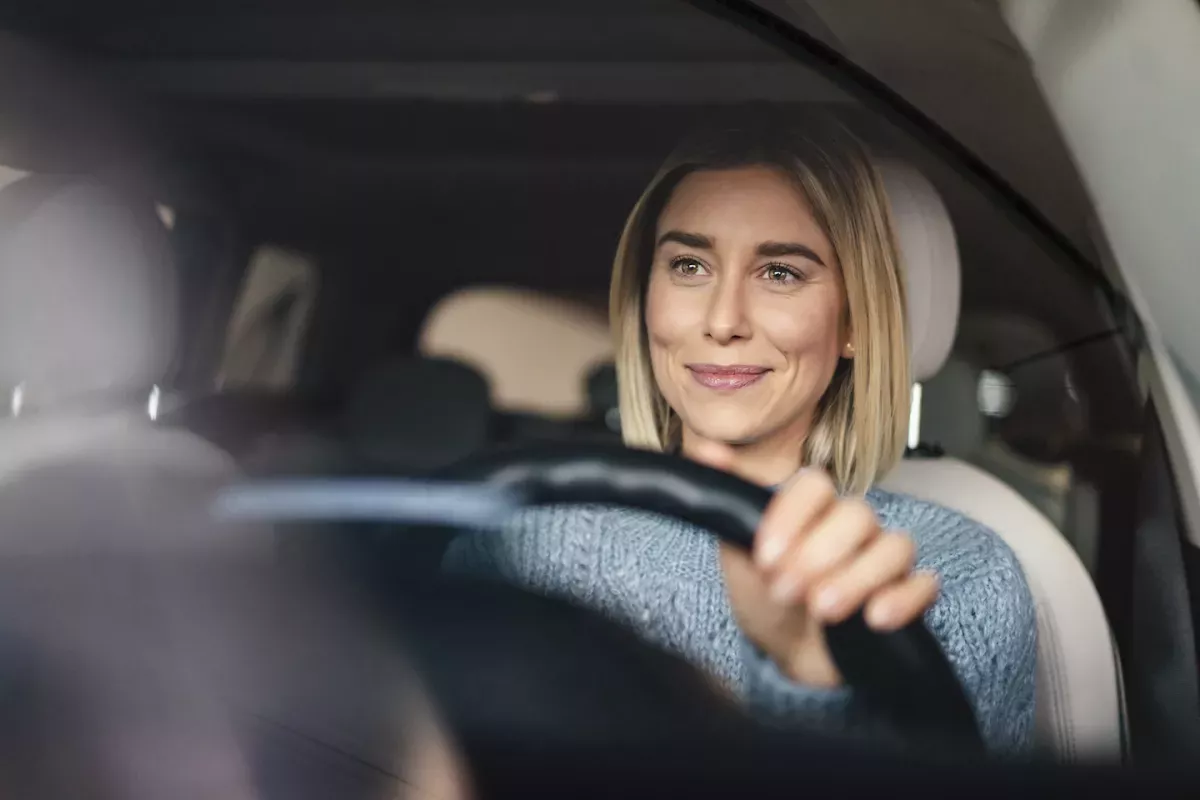 GettyImages-1193069476.jpg Woman smiling and driving a car