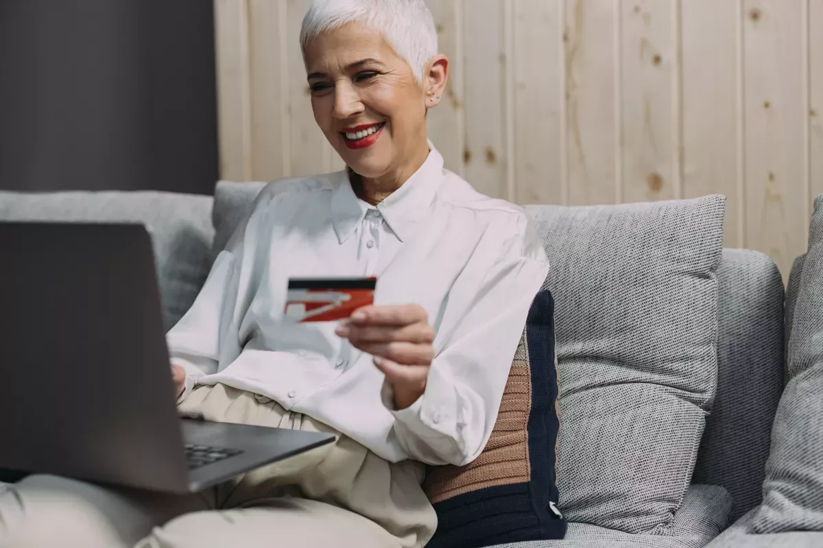 GettyImages-1317337937.jpg smiling woman holding credit card and using laptop
