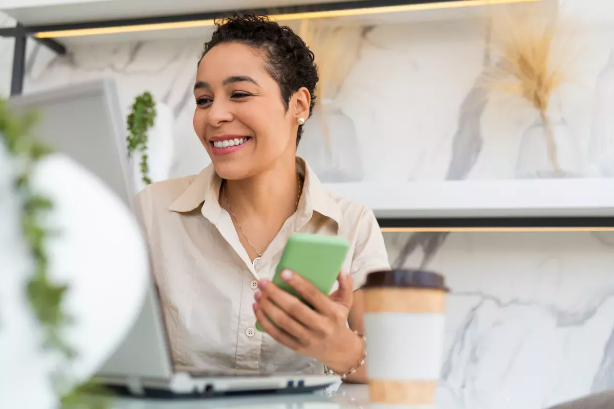 GettyImages-1343887457_Scoring Strategies smiling woman using laptop and cell phone
